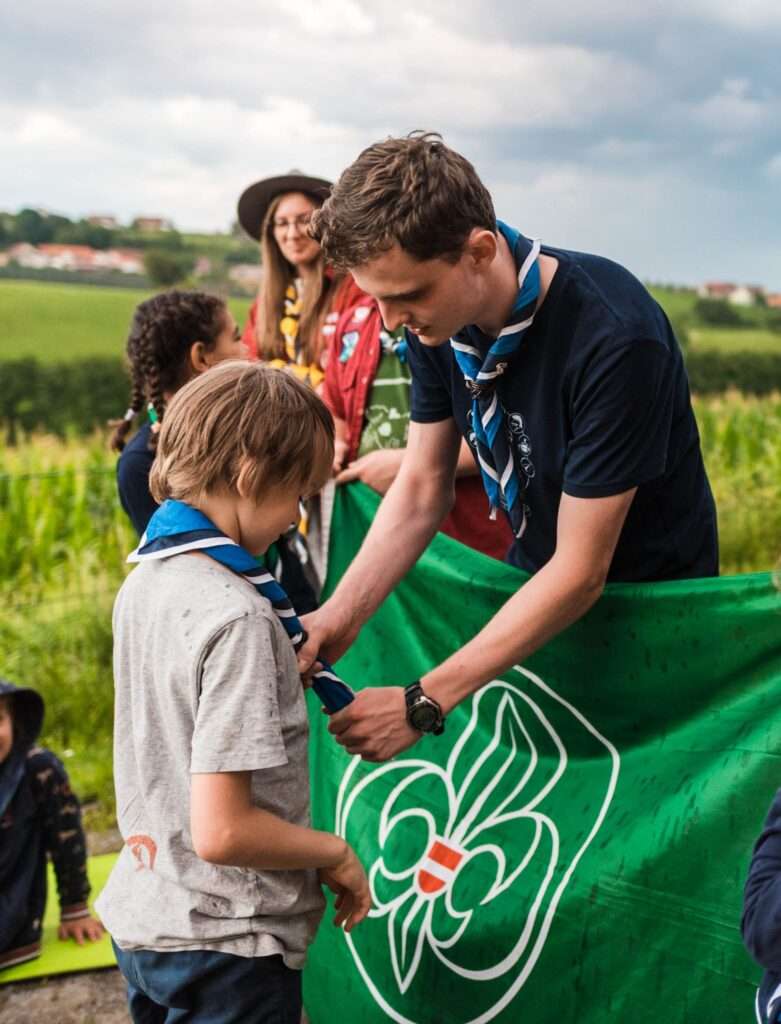Leiter verleiht einem Kind ein Pfadfinderhalstuch